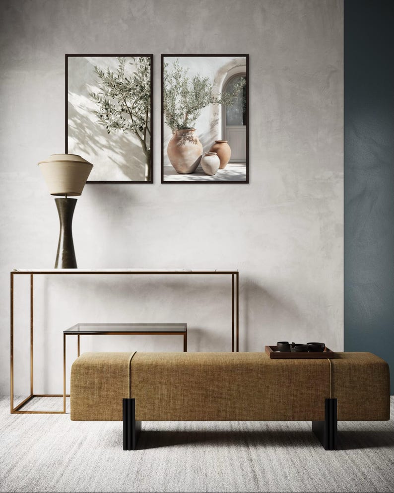 Puede incluir: Una escena de dise&ntilde;o de interiores con dos estampados bot&aacute;nicos enmarcados, una l&aacute;mpara de mesa, una consola, una peque&ntilde;a mesa auxiliar y un banco. El banco est&aacute; tapizado en tela color beige y tiene patas negras. Los estampados representan ramas de olivo y jarrones.