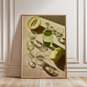 May include: A framed still life featuring a clear glass bottle and several drinking glasses, all filled with a light green liquid. Slices of green melon and ice cubes are also present, suggesting a refreshing beverage. The image is set against a neutral background.