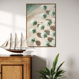 May include: An aerial view of a beach with rows of green umbrellas on the sand.