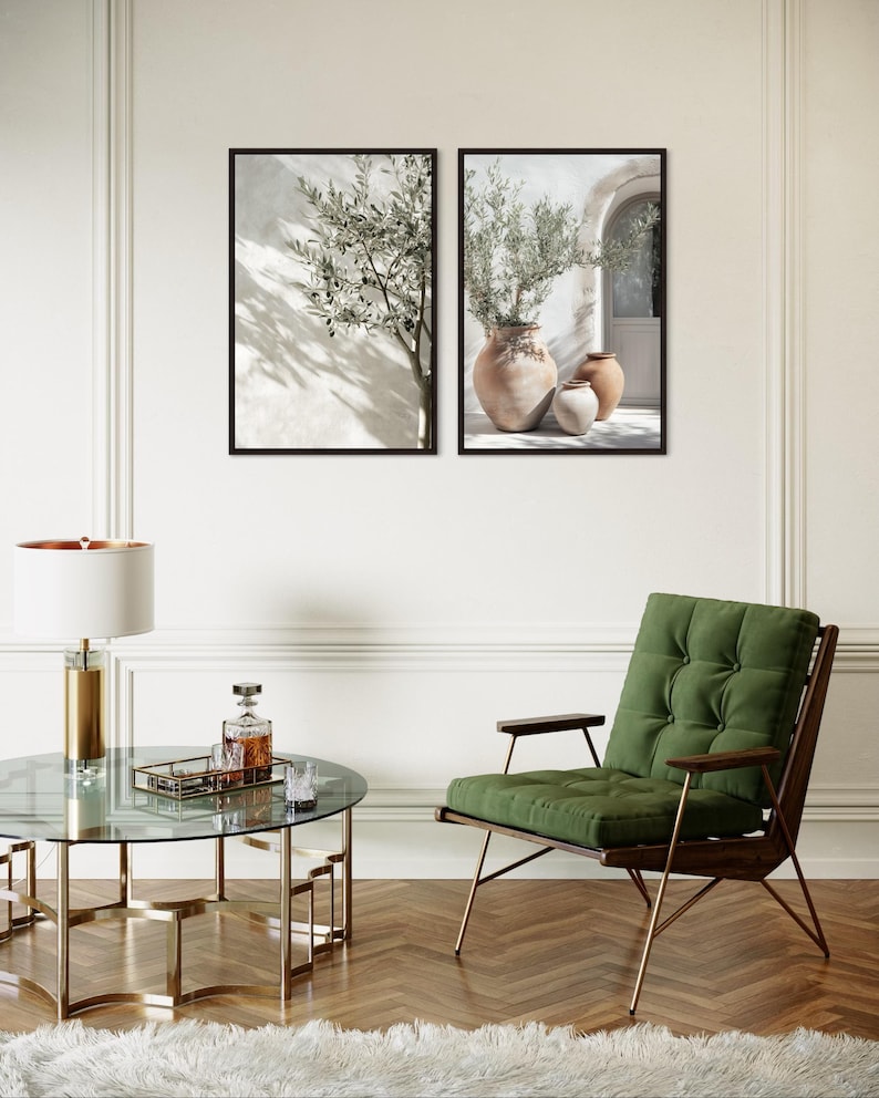 Puede incluir: Dos impresiones art&iacute;sticas enmarcadas con ramas de olivo en jarrones, exhibidas en una pared blanca. Una mesa de centro redonda de cristal con base dorada, un sill&oacute;n verde y una l&aacute;mpara dorada completan la decoraci&oacute;n.