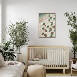 May include: A framed print of an aerial view of a beach with green umbrellas and white sand. The print is hanging on a white wall in a nursery with a crib and a plant.