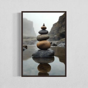 May include: A stack of smooth, gray and brown stones balanced on top of each other in a zen garden setting. The stones are reflected in the still water below.