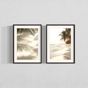 Puede incluir: Dos impresiones enmarcadas de escenas de playa tropical. La impresi&oacute;n de la izquierda muestra sombras de palmeras en una playa de arena. La impresi&oacute;n de la derecha muestra una palmera en una playa con olas rompiendo en la orilla.