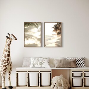 Puede incluir: Dos impresiones enmarcadas de escenas de playa tropical con palmeras y arena blanca. Las impresiones est&aacute;n colgadas en una pared blanca sobre un banco de madera con contenedores de almacenamiento blancos. Una jirafa de peluche y un conejito de peluche est&aacute;n en el suelo frente al banco.