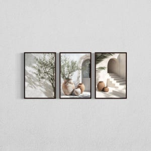 Op de afbeelding: Een set van drie ingelijste wandkunstprints met mediterrane scènes. De eerste toont een olijfboom, de tweede drie terracotta vazen met groen, en de derde toont een stenen trap met twee kleipotten in een lichte, zonnige omgeving.