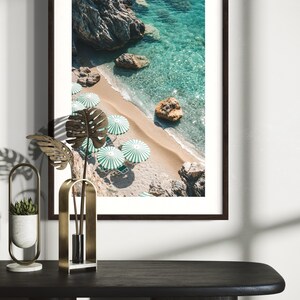 May include: An aerial view of a beach with turquoise water and white sand. Green and white striped umbrellas line the beach.