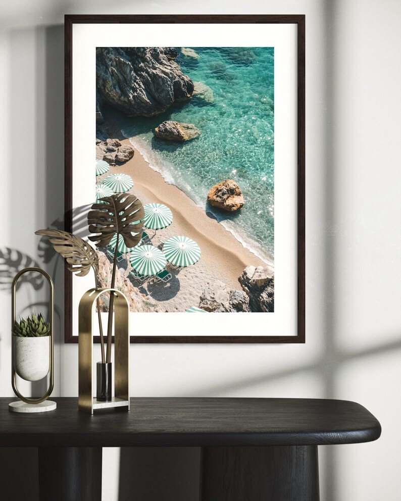 May include: An aerial view of a beach with turquoise water and white sand. Green and white striped umbrellas line the beach.