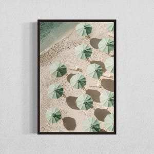 May include: An aerial view of a sandy beach with rows of green umbrellas and white lounge chairs.
