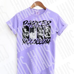 Pode incluir: Uma t-shirt lil&aacute;s clara com uma imagem a preto e branco de Parker McCollum. O texto "PARKER MCCOLLUM" est&aacute; impresso a preto acima e abaixo das imagens. A t-shirt est&aacute; pendurada num cabide de madeira.