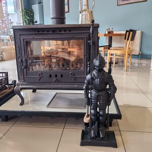 Medieval knight fireplace accessory set with poker, brush, tongs, and shovel in a rustic cast iron design, ideal for home decor.