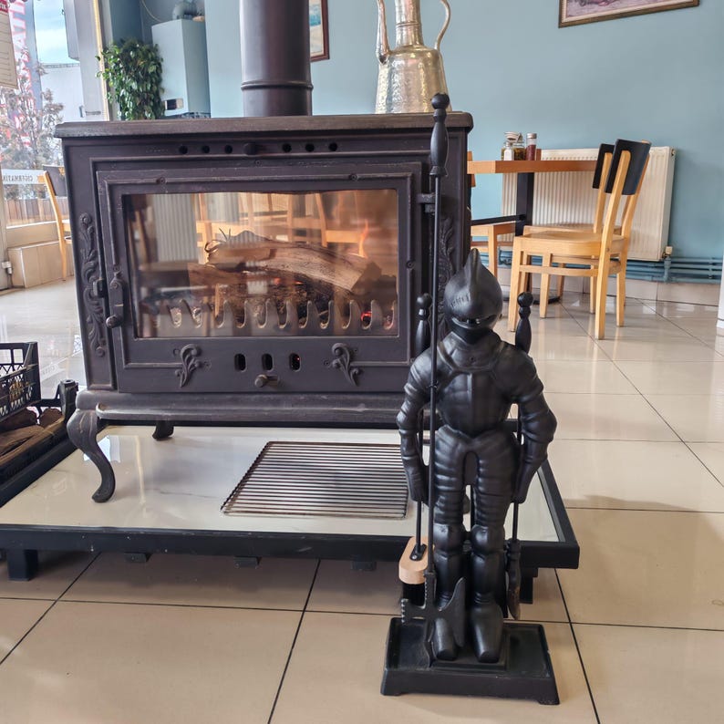 Medieval knight fireplace accessory set with poker, brush, tongs, and shovel in a rustic cast iron design, ideal for home decor.