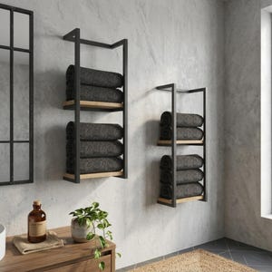 Black metal towel holder with wooden shelves and folded towels