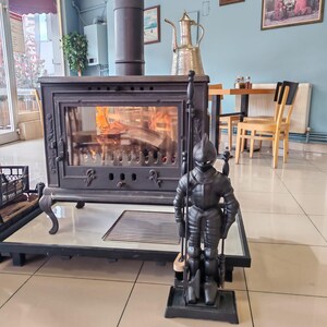 Unique knight-shaped stand holding a complete set of fireplace tools, perfect for enhancing a fireplace's medieval charm.