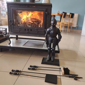 Medieval knight fireplace accessory set with poker, brush, tongs, and shovel in a rustic cast iron design, ideal for home decor.