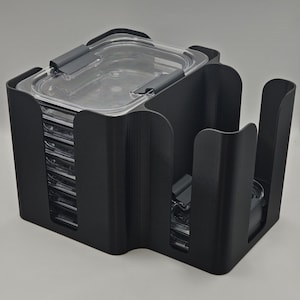 May include: A black plastic food storage container organizer. The organizer has multiple compartments to hold clear, rectangular food containers with gray lids. The containers are stacked inside the organizer, which has a curved design.