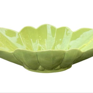 Peut inclure: Un saladier en céramique vert clair avec un bord festonné. Le bol a une finition brillante et une conception peu profonde et large. Le bol est probablement utilisé pour servir des aliments ou comme pièce décorative.