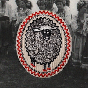 May include: Embroidered patch featuring a sheep design. The sheep has a white face and black wool made of spiral patterns. The patch is bordered with red and black stitching. The background is a black and white photo of people.