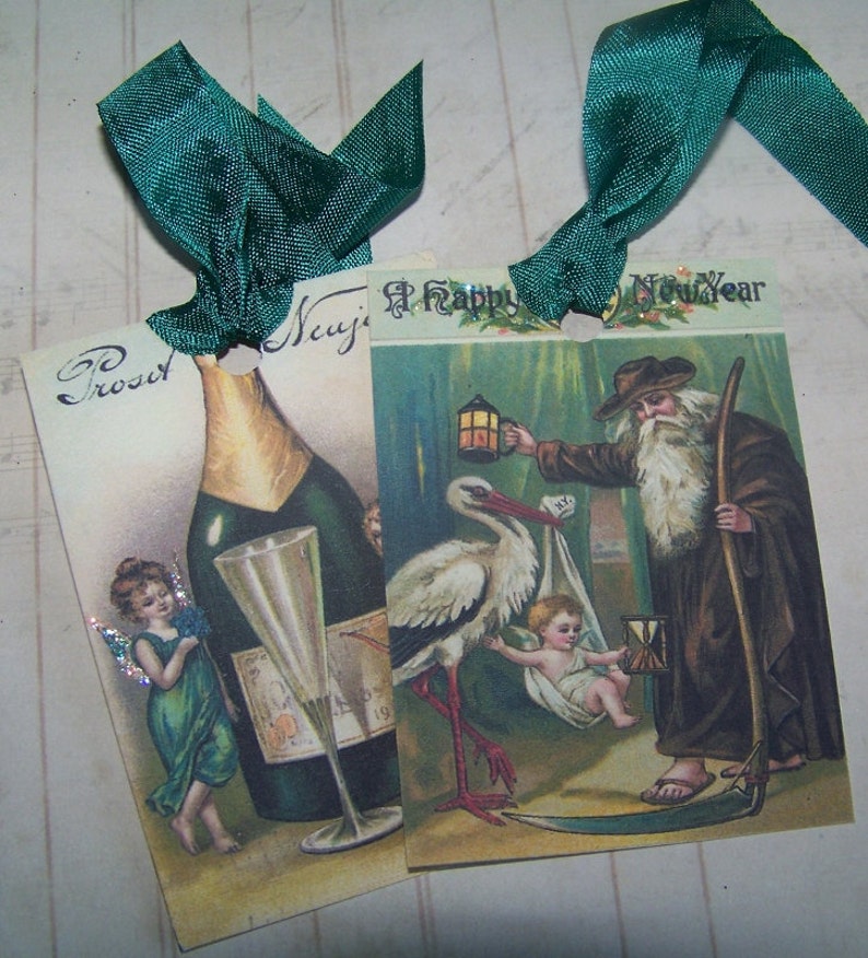 May include: Two vintage Christmas gift tags with green ribbon. The first tag features a bottle of champagne with a glass and a fairy with green wings. The second tag features a stork carrying a baby, a man with a lantern and the text "A Happy New Year".