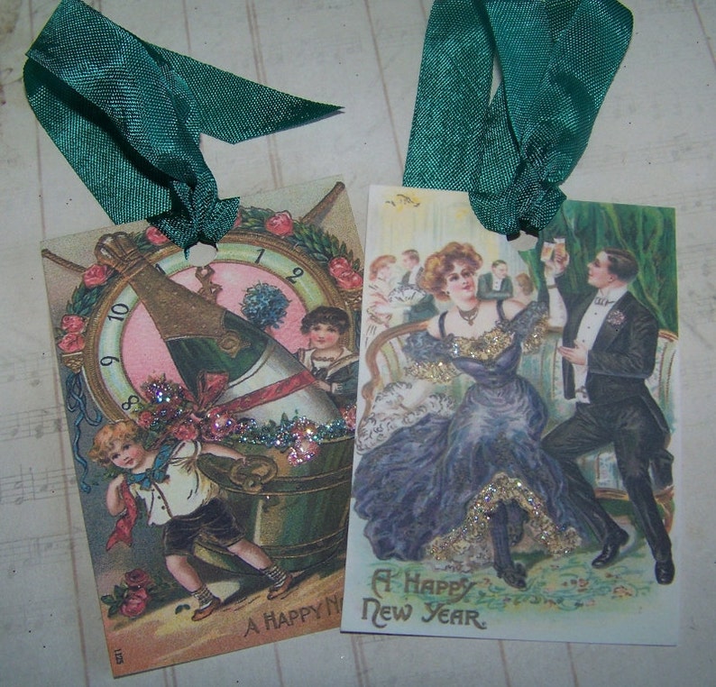 May include: Two vintage New Year's Eve gift tags with green ribbon. One tag features a champagne bottle with a clock face and the text "A Happy New Year". The other tag features a couple dancing with the text "A Happy New Year".