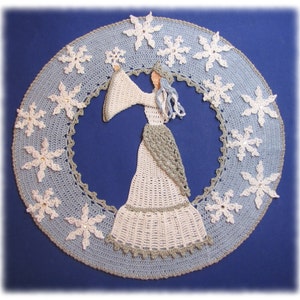 May include: A crocheted snowflake doily with a white crocheted figure of a woman in the center. The doily is blue and white with a gray border.