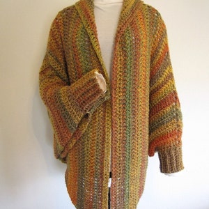 May include: A crochet cardigan with a long, open front and bell sleeves. The cardigan is made with a multi-coloured yarn in shades of brown, orange, and green. The text "PDF Pattern" is visible at the top of the image.