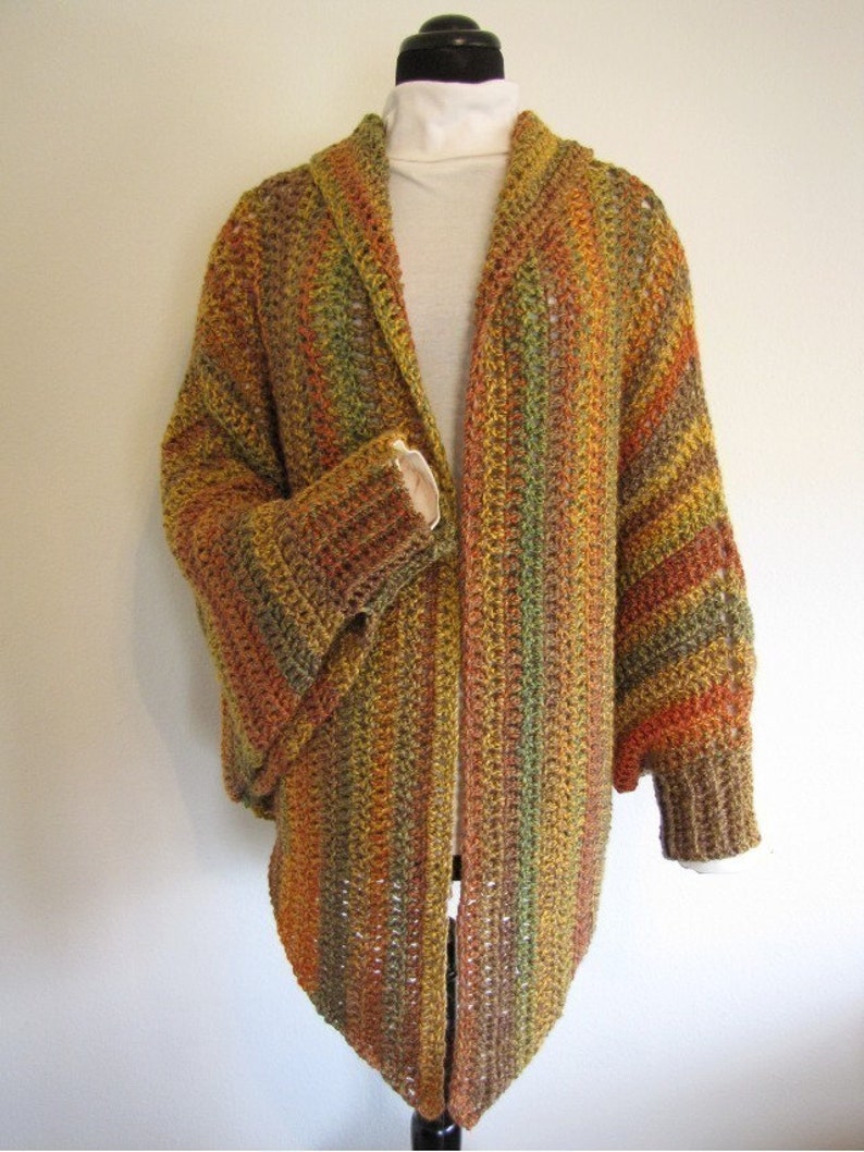 Op de afbeelding: Een lange, open cardigan met een gestreept patroon in tinten bruin, oranje en groen. De cardigan heeft een brede shawlkraag en lange mouwen.