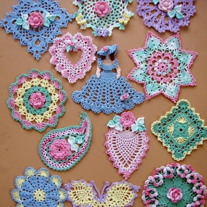May include: A collection of 12 crocheted doilies in various shapes and colors, including a butterfly, a paisley, a star, and a heart. The doilies are made with delicate stitches and feature floral motifs.