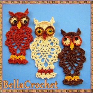Puede incluir: Tres adornos de búho hechos a crochet en rojo, blanco y marrón. Los búhos tienen ojos de botón negro y picos amarillos. Los búhos están sobre un fondo azul.