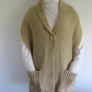 May include: A beige crocheted vest with a large collar, a button closure, and two pockets.