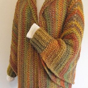 Op de afbeelding: Een gebreide cardigan met een coltrui en lange mouwen. De cardigan is gemaakt van een meerkleurig garen in tinten bruin, oranje en groen.