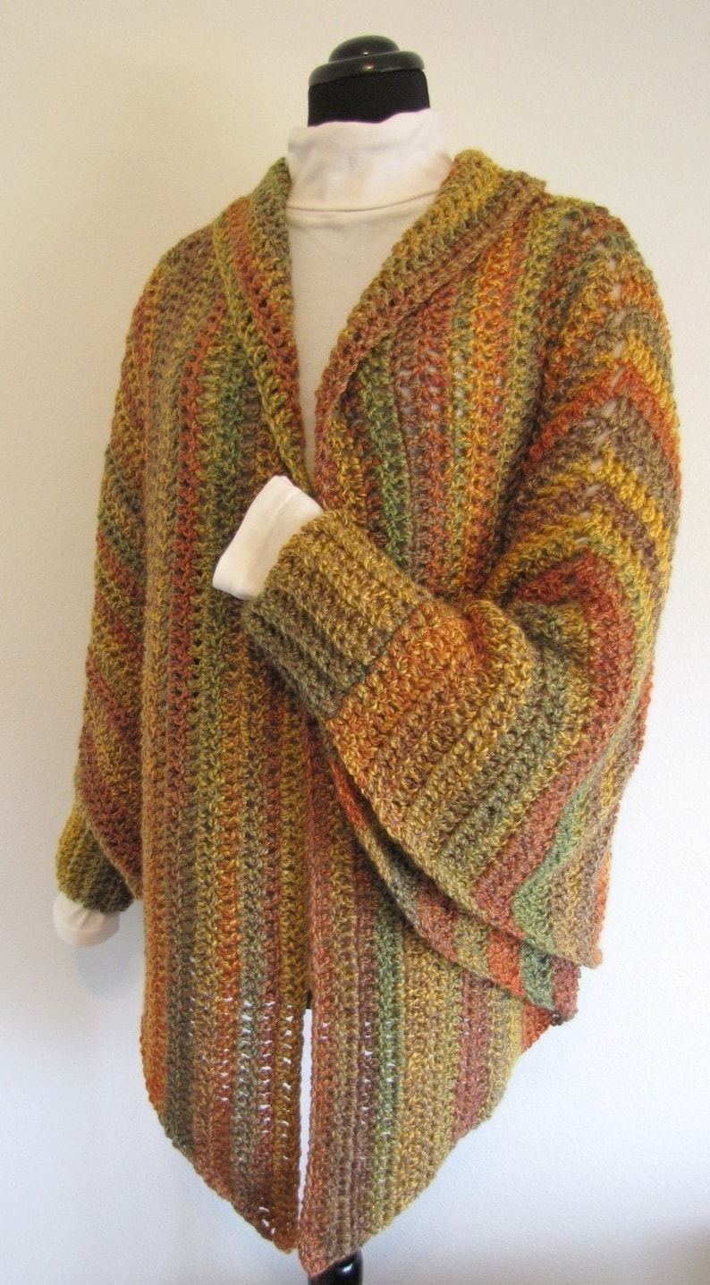 Op de afbeelding: Een gebreide cardigan met een coltrui en lange mouwen. De cardigan is gemaakt van een meerkleurig garen in tinten bruin, oranje en groen.