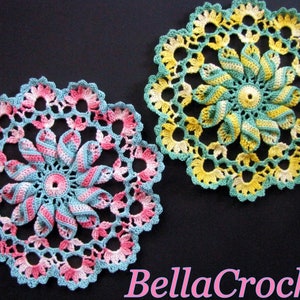 May include: Two crocheted doilies with a floral design. One doily is green, yellow, and white. The other doily is pink, blue, and white.