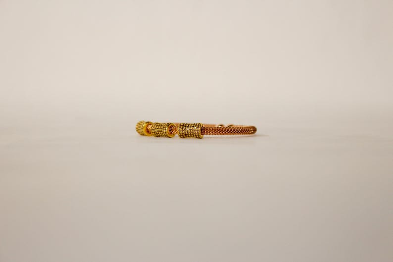 Unique golden mesh bracelet, adorned with vibrant crystals for a pop of color. The three meticulously crafted crystal-encrusted cylindrical accents create a perfect balance of elegance and modern style. Lightweight and comfortable for versatile use.
