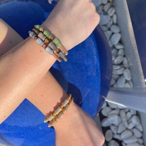 Unique golden mesh bracelet, adorned with vibrant crystals for a pop of color. The three meticulously crafted crystal-encrusted cylindrical accents create a perfect balance of elegance and modern style. Lightweight and comfortable for versatile use.