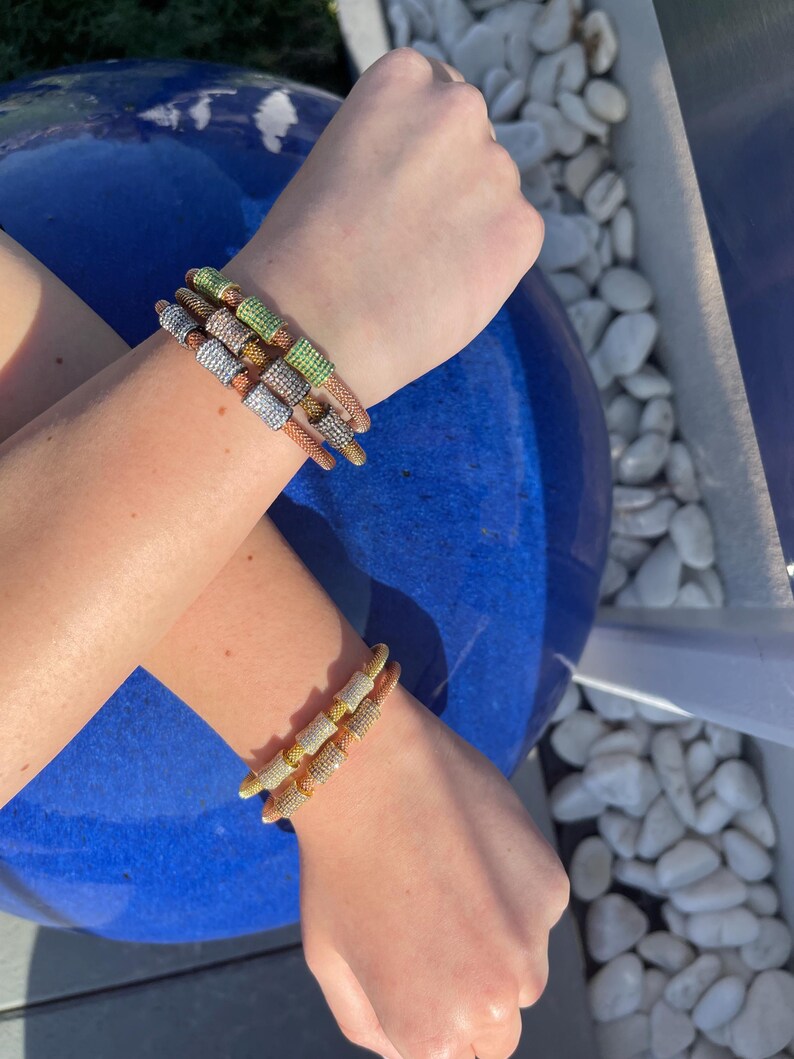 Unique golden mesh bracelet, adorned with vibrant crystals for a pop of color. The three meticulously crafted crystal-encrusted cylindrical accents create a perfect balance of elegance and modern style. Lightweight and comfortable for versatile use.