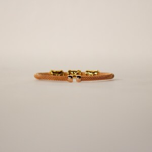 Unique golden mesh bracelet, adorned with vibrant crystals for a pop of color. The three meticulously crafted crystal-encrusted cylindrical accents create a perfect balance of elegance and modern style. Lightweight and comfortable for versatile use.