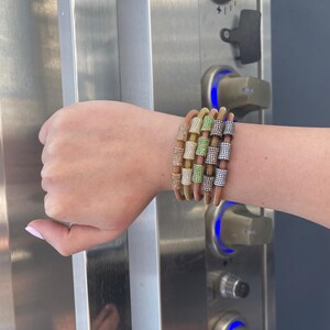 Unique golden mesh bracelet, adorned with vibrant crystals for a pop of color. The three meticulously crafted crystal-encrusted cylindrical accents create a perfect balance of elegance and modern style. Lightweight and comfortable for versatile use.