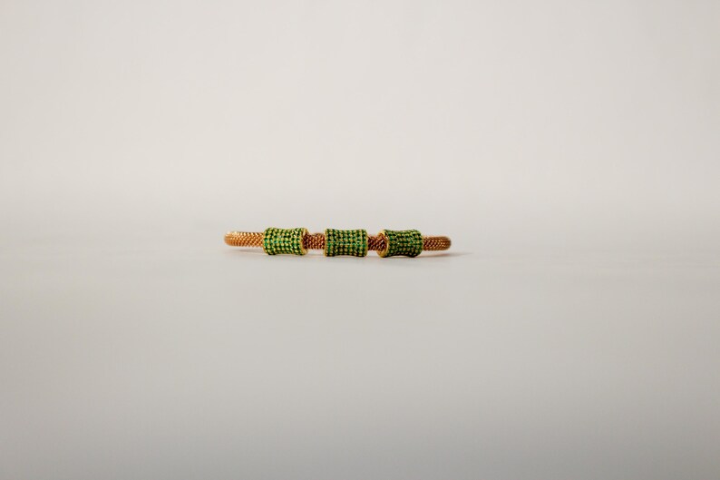 Unique golden mesh bracelet, adorned with vibrant crystals for a pop of color. The three meticulously crafted crystal-encrusted cylindrical accents create a perfect balance of elegance and modern style. Lightweight and comfortable for versatile use.