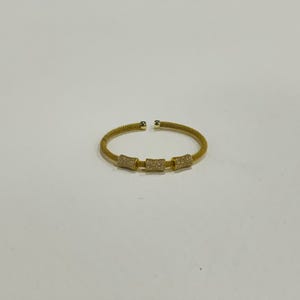 Unique golden mesh bracelet, adorned with vibrant crystals for a pop of color. The three meticulously crafted crystal-encrusted cylindrical accents create a perfect balance of elegance and modern style. Lightweight and comfortable for versatile use.