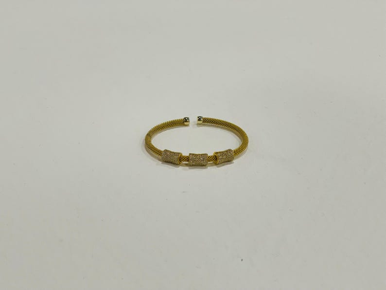 Unique golden mesh bracelet, adorned with vibrant crystals for a pop of color. The three meticulously crafted crystal-encrusted cylindrical accents create a perfect balance of elegance and modern style. Lightweight and comfortable for versatile use.