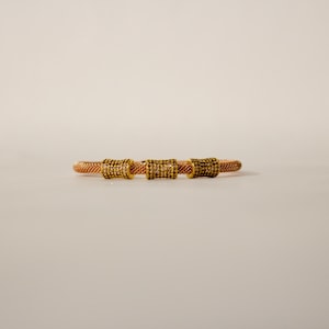 Unique golden mesh bracelet, adorned with vibrant crystals for a pop of color. The three meticulously crafted crystal-encrusted cylindrical accents create a perfect balance of elegance and modern style. Lightweight and comfortable for versatile use.