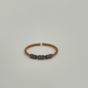 Unique golden mesh bracelet, adorned with vibrant crystals for a pop of color. The three meticulously crafted crystal-encrusted cylindrical accents create a perfect balance of elegance and modern style. Lightweight and comfortable for versatile use.
