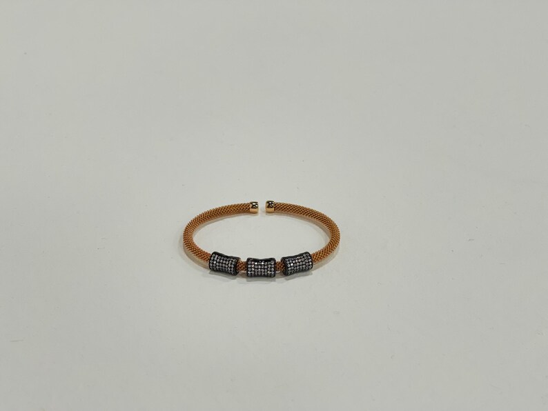 Unique golden mesh bracelet, adorned with vibrant crystals for a pop of color. The three meticulously crafted crystal-encrusted cylindrical accents create a perfect balance of elegance and modern style. Lightweight and comfortable for versatile use.