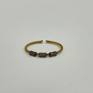 Unique golden mesh bracelet, adorned with vibrant crystals for a pop of color. The three meticulously crafted crystal-encrusted cylindrical accents create a perfect balance of elegance and modern style. Lightweight and comfortable for versatile use.