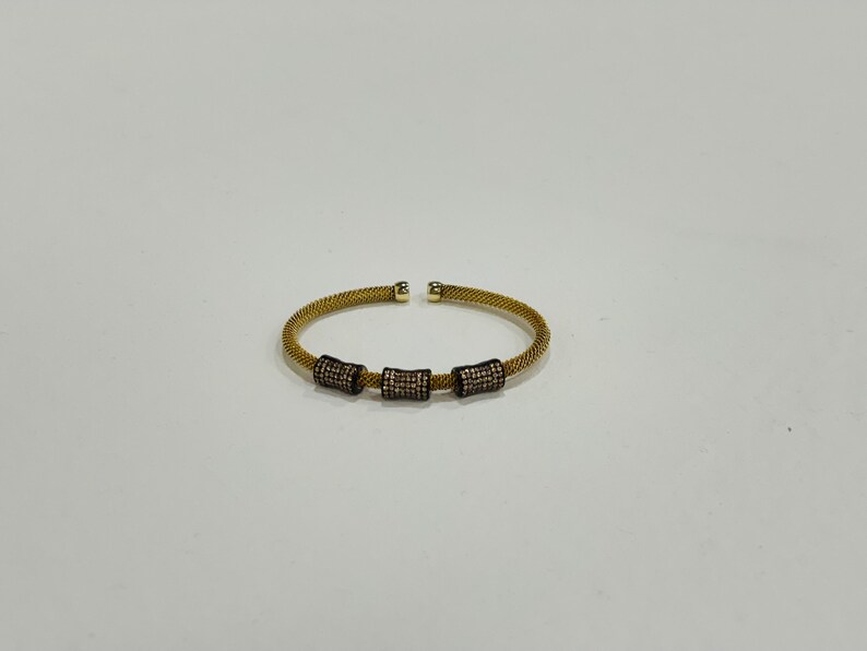 Unique golden mesh bracelet, adorned with vibrant crystals for a pop of color. The three meticulously crafted crystal-encrusted cylindrical accents create a perfect balance of elegance and modern style. Lightweight and comfortable for versatile use.