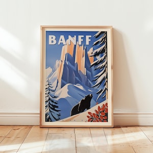 Peut inclure: Une affiche encadrée présentant un design de poster de voyage vintage pour Banff. L'affiche représente une chaîne de montagnes enneigées, un ours et le mot "BANFF" en grandes lettres blanches. La palette de couleurs comprend le bleu, l'orange et le blanc.
