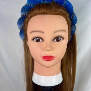 May include: A blue velvet headband with a silver chain detail. The headband is worn on a mannequin with long brown hair.