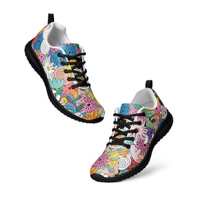 May include: A pair of black and white trainers with a colourful floral print. The trainers have black laces and a white sole.