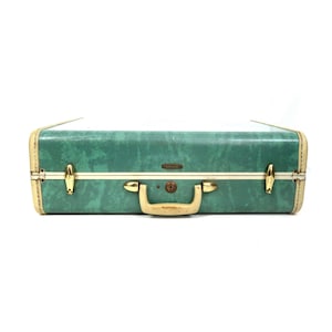 May include: Vintage green suitcase with gold-tone hardware. The suitcase features a marbled pattern, a tan trim, and a gold handle. The suitcase has a keyhole lock and is likely from the mid-20th century. A classic travel accessory.