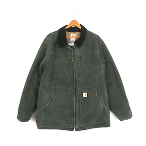 May include: A dark green work jacket with a black corduroy collar, a zip-up front, and two large front pockets. The jacket has a small logo patch on the front pocket and is hanging on a wooden hanger.